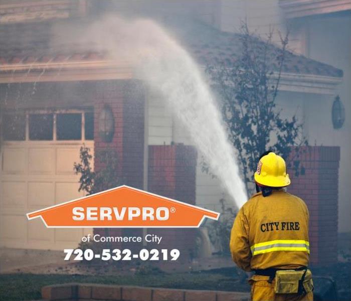 A firefighter is shown spraying water on a home to extinguish a fire.